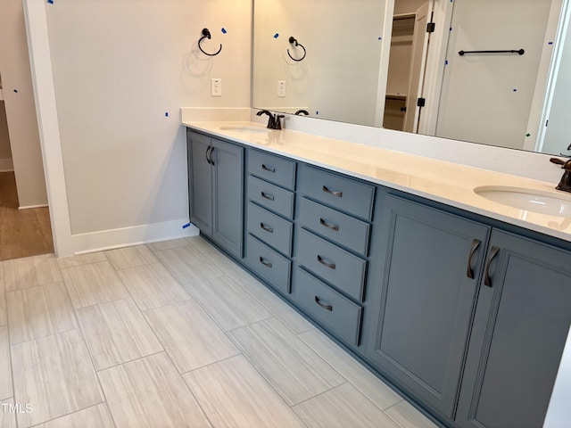 full bathroom featuring a sink, a spacious closet, baseboards, and double vanity