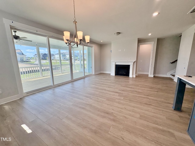 unfurnished living room with light wood-style flooring, stairway, a notable chandelier, and baseboards