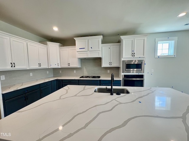 kitchen featuring a sink, backsplash, white cabinets, and stainless steel appliances