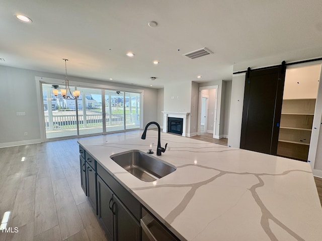 kitchen with light wood-style floors, visible vents, a barn door, a sink, and open floor plan