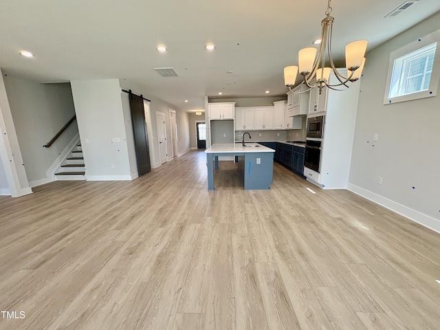 kitchen featuring open floor plan, stainless steel microwave, a barn door, and visible vents