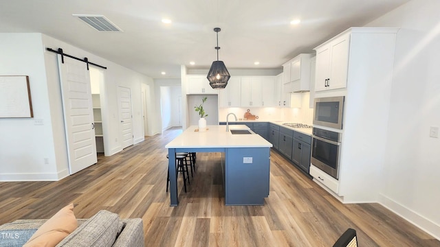 1237 Porters Call Dr, Wendell, NC 27591 - kitchen featuring appliances with stainless steel finishes, a barn door, white cabinetry, recessed lighting, and wood finished floors