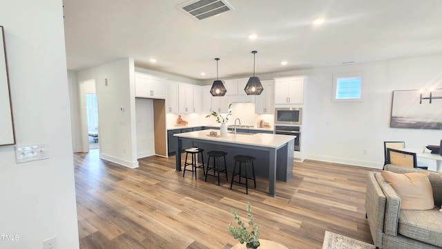1237 Porters Call Dr, Wendell, NC 27591 - kitchen featuring appliances with stainless steel finishes, open floor plan, a breakfast bar, white cabinetry, and recessed lighting