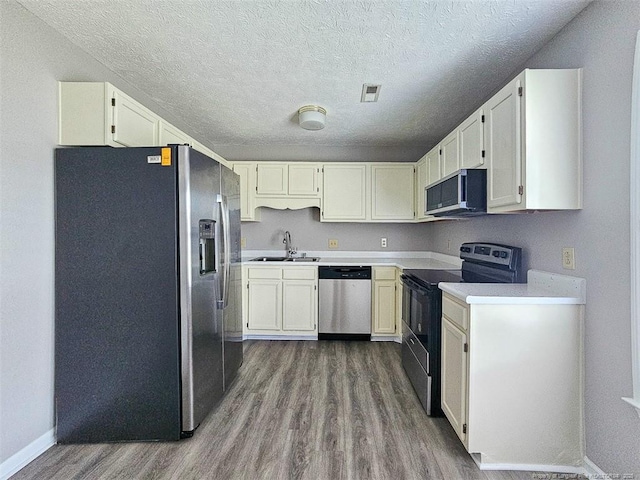 kitchen with a textured ceiling, dark wood-style flooring, light countertops, a sink, and stainless steel appliances