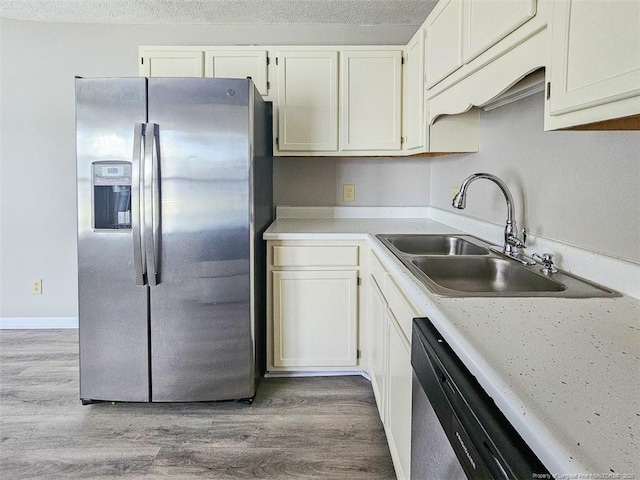 kitchen with light wood-style floors, a textured ceiling, light countertops, a sink, and stainless steel appliances