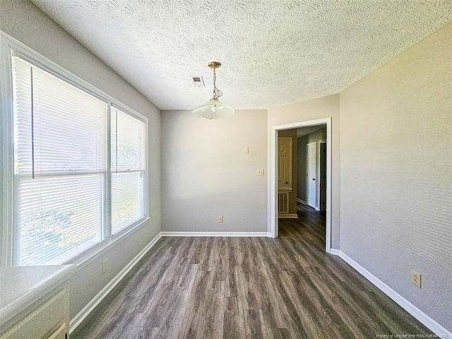 unfurnished room featuring a textured ceiling, baseboards, dark wood finished floors, and visible vents