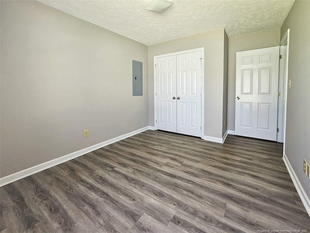 unfurnished bedroom featuring electric panel, dark wood-type flooring, and baseboards