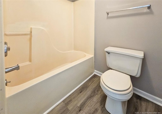 full bath featuring toilet, wood finished floors, baseboards, and bathtub / shower combination