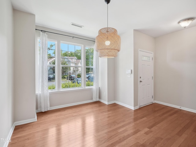unfurnished dining area featuring baseboards, wood finished floors, and visible vents