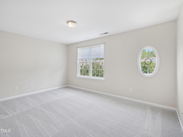 empty room featuring visible vents, carpet, baseboards, and a healthy amount of sunlight