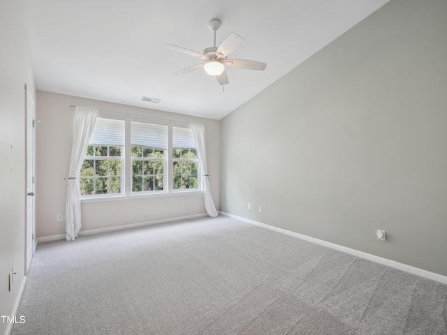carpeted spare room with a ceiling fan, baseboards, visible vents, and vaulted ceiling
