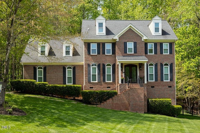 georgian-style home with brick siding, a front lawn, and crawl space