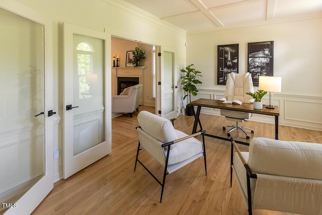 office with coffered ceiling, crown molding, french doors, wainscoting, and a fireplace