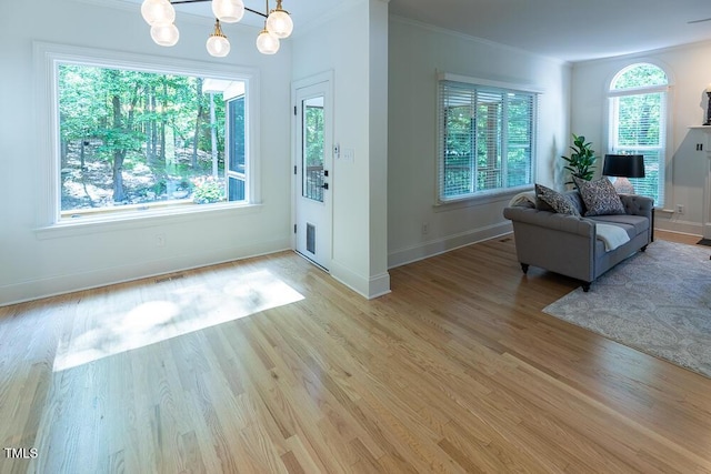 foyer with ornamental molding, baseboards, light wood-style floors, and a chandelier