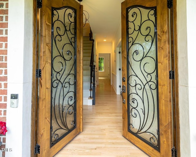 hallway featuring light wood-style floors, stairway, and crown molding