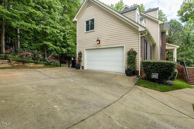 view of property exterior featuring concrete driveway, a garage, and fence