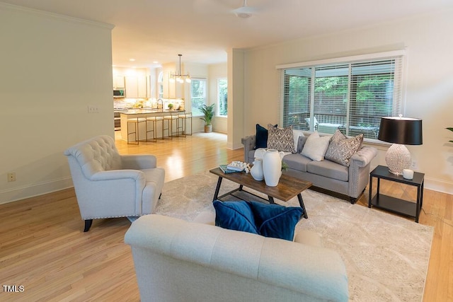living area featuring a chandelier, light wood-style floors, and baseboards