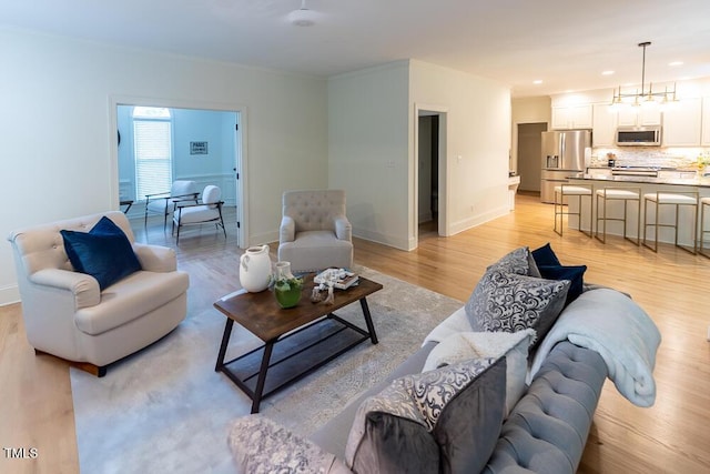 living area with ornamental molding, light wood-style flooring, recessed lighting, and baseboards