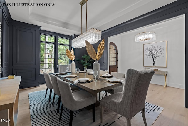 dining area featuring a tray ceiling, light wood-type flooring, and a notable chandelier