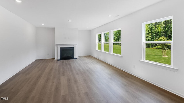 unfurnished living room with wood finished floors, recessed lighting, a fireplace with flush hearth, and baseboards