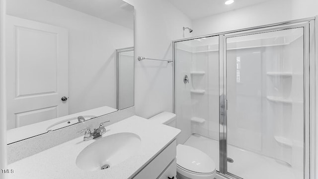 bathroom featuring toilet, a shower stall, and vanity
