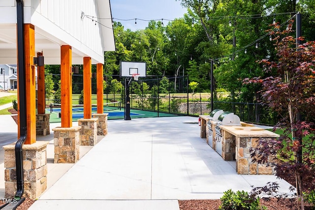 view of patio with area for grilling, fence, and community basketball court