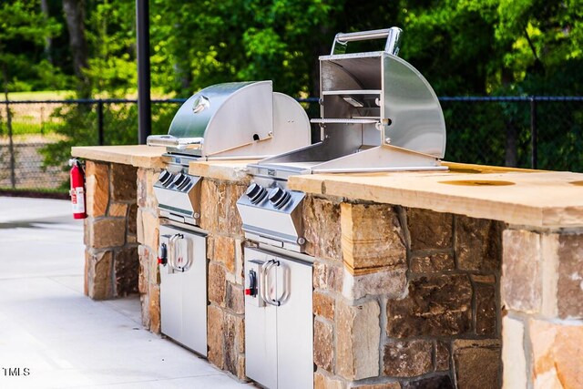 view of patio / terrace with exterior kitchen, fence, and a grill
