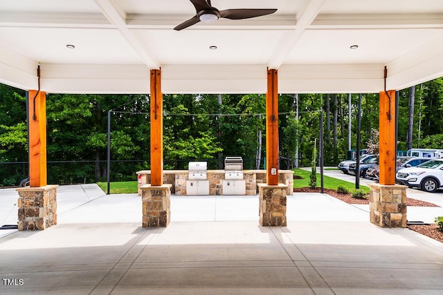 view of patio / terrace with ceiling fan, an outdoor kitchen, a grill, and view of wooded area