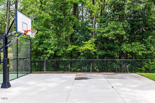 view of basketball court featuring basketball hoop and fence