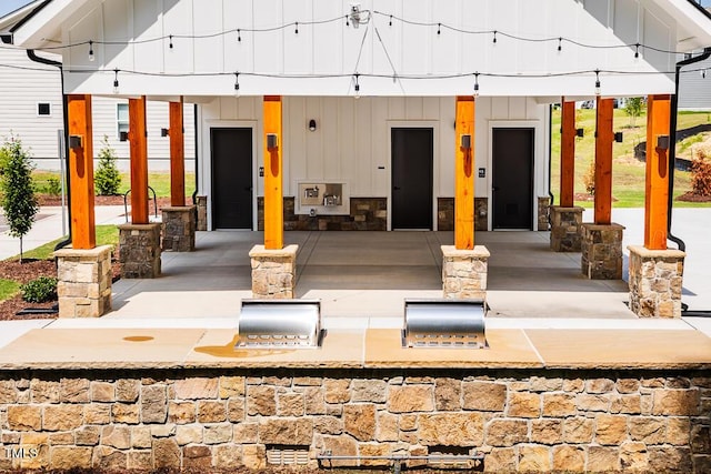 exterior space featuring board and batten siding, stone siding, and area for grilling