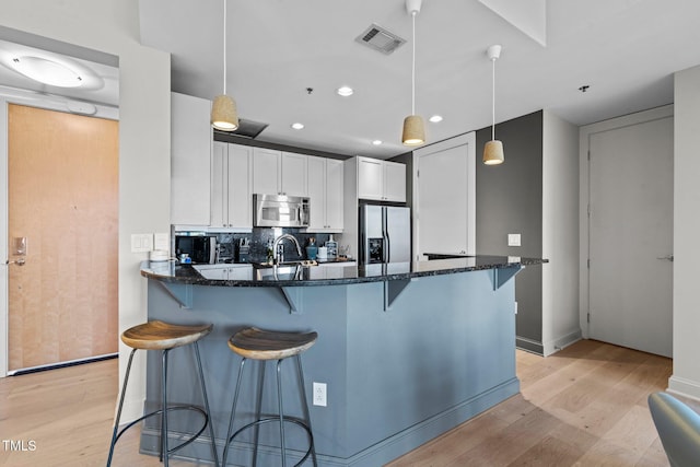 kitchen featuring stainless steel appliances, light wood finished floors, white cabinetry, a peninsula, and recessed lighting