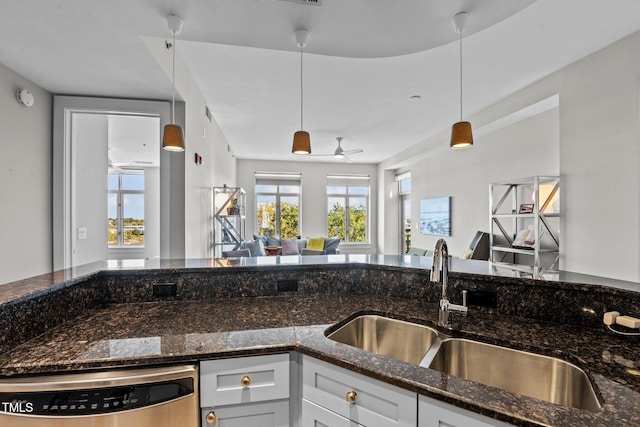 kitchen featuring dishwasher, a sink, open floor plan, and dark stone countertops