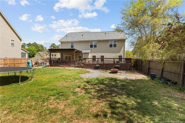 4016 Baywood Point Dr, Fayetteville, NC 28312 - rear view of property featuring a fenced backyard, an outdoor fire pit, a trampoline, and a deck