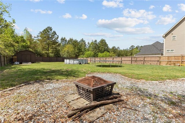 4016 Baywood Point Dr, Fayetteville, NC 28312 - view of yard featuring a trampoline, a fire pit, a fenced backyard, an outbuilding, and a storage unit