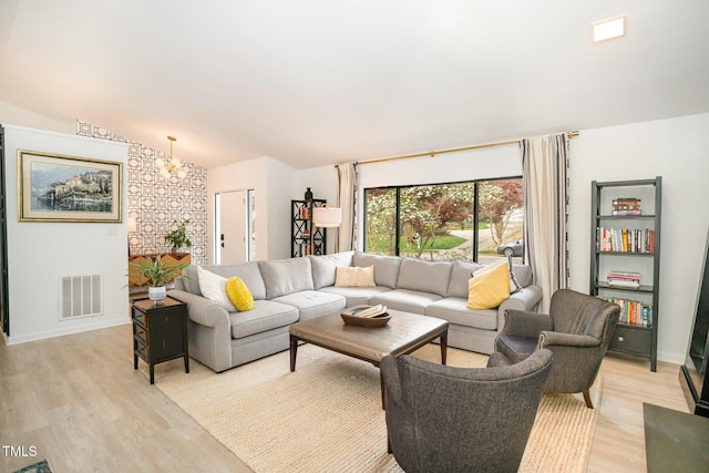 living area with lofted ceiling, baseboards, visible vents, and light wood-type flooring