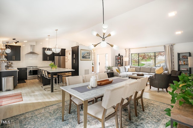 dining room featuring visible vents, light wood-type flooring, and lofted ceiling