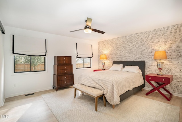 bedroom with visible vents, baseboards, multiple windows, and light wood-style floors