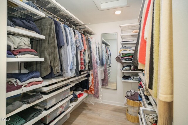 walk in closet featuring attic access and wood finished floors