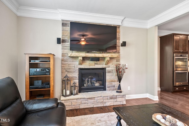 living room featuring crown molding, a stone fireplace, wood finished floors, and baseboards