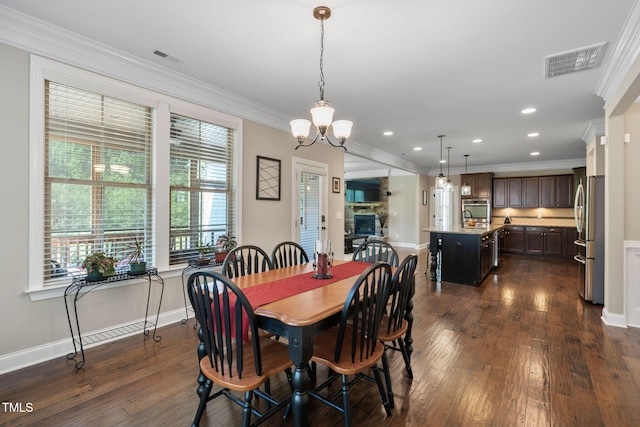 dining area with ornamental molding, visible vents, a notable chandelier, and dark wood finished floors