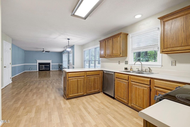 3900 Inkberry Ct, Apex, NC 27539 - kitchen featuring stainless steel dishwasher, a peninsula, light wood-style floors, brown cabinetry, and a glass covered fireplace