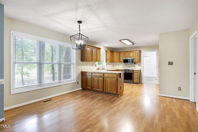 3900 Inkberry Ct, Apex, NC 27539 - kitchen with appliances with stainless steel finishes, light wood-type flooring, light countertops, a peninsula, and a chandelier