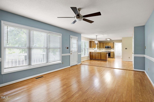 3900 Inkberry Ct, Apex, NC 27539 - unfurnished living room featuring a ceiling fan, light wood-style floors, and a textured ceiling