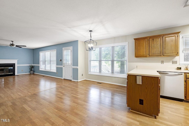 3900 Inkberry Ct, Apex, NC 27539 - kitchen featuring dishwasher, a ceiling fan, light countertops, a glass covered fireplace, and light wood-type flooring