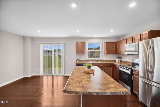 1004 Summer Mist Ln, Durham, NC 27704 - kitchen with appliances with stainless steel finishes, recessed lighting, dark wood-type flooring, a center island, and brown cabinetry