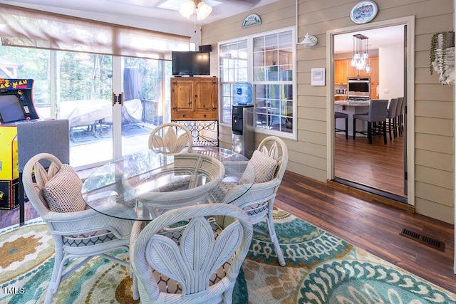 dining space featuring wood walls, wood finished floors, and visible vents