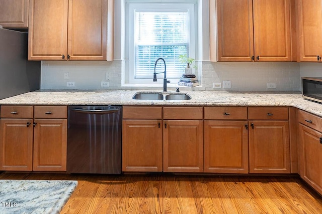 kitchen with a sink, appliances with stainless steel finishes, light stone countertops, and tasteful backsplash