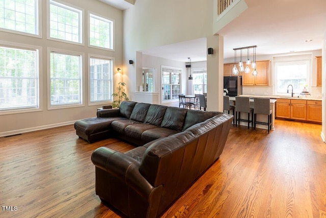 living room featuring plenty of natural light, light wood-style flooring, and a high ceiling