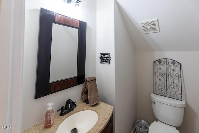 bathroom with toilet, visible vents, vaulted ceiling, and vanity
