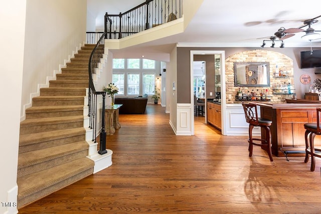 bar featuring a bar, wood finished floors, and stairway